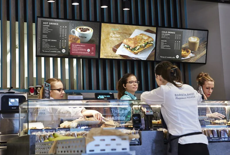 Digital menu boards above the counter in a cafe